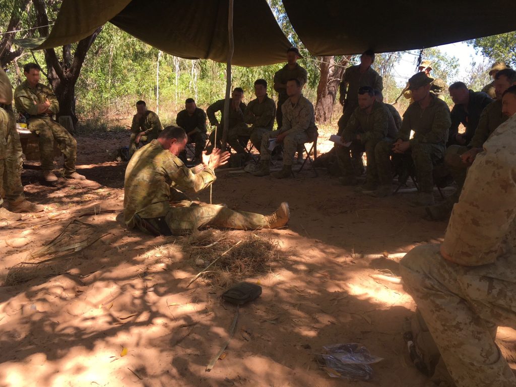 The author teaching soldiers on an army survival course how to make fire using a traditional friction fire method known as the hand drill